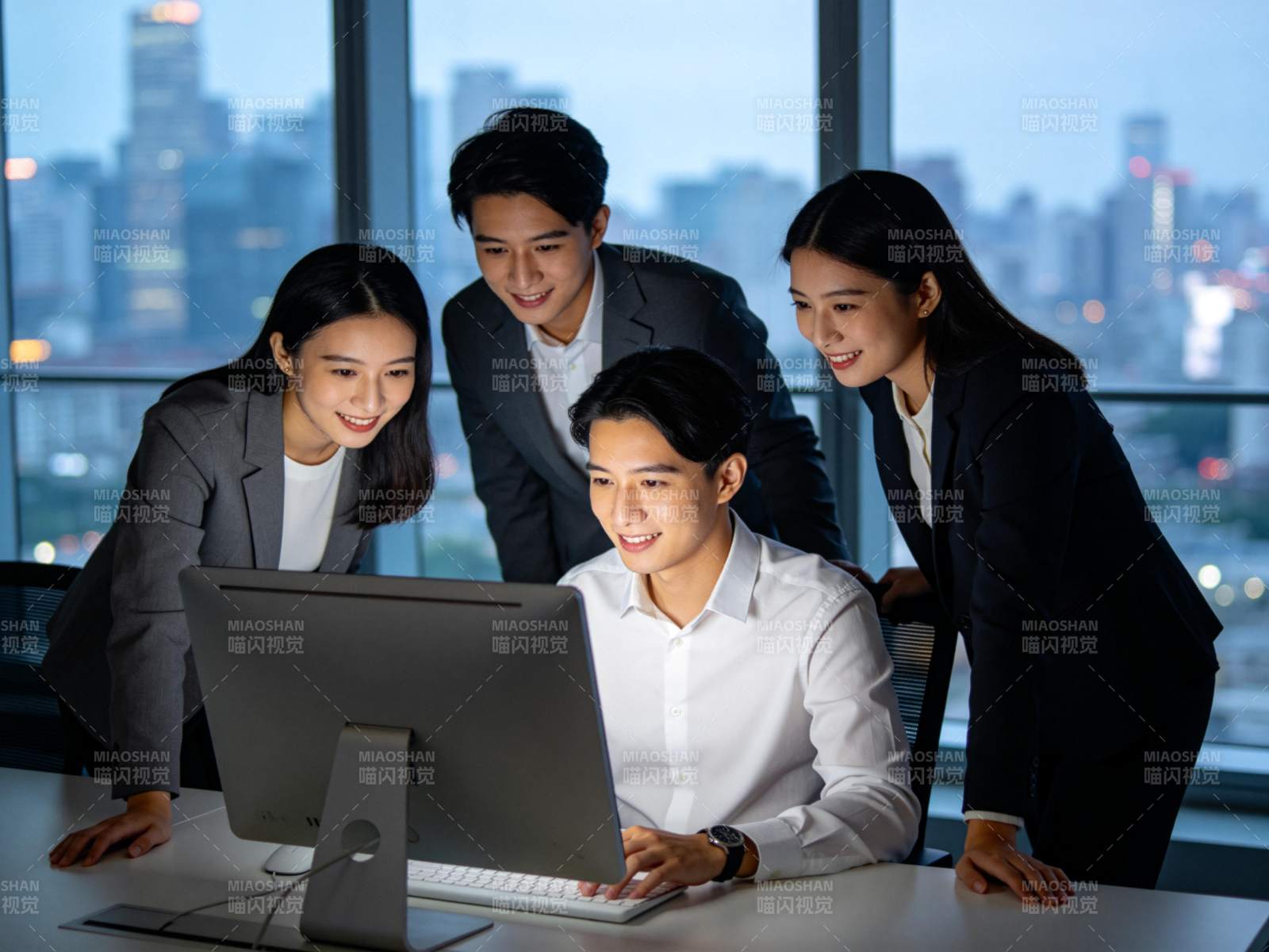 四位职场人员围看电脑屏幕讨论工作内容图片
