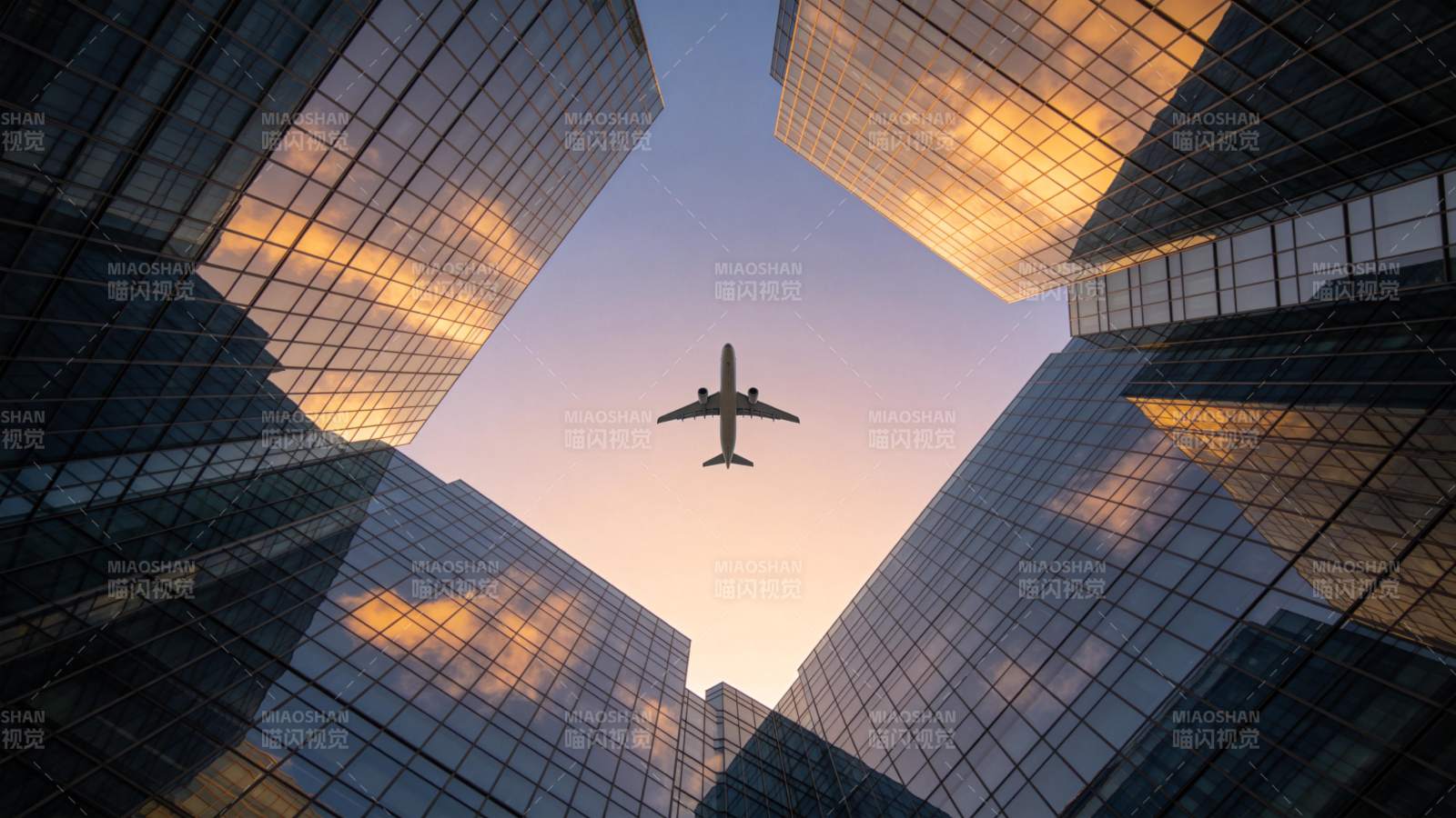 高楼间飞行的客机与玻璃幕墙倒影图片