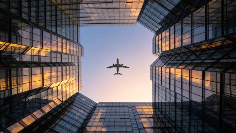 玻璃幕墙高楼间飞行的客机仰拍视角图片