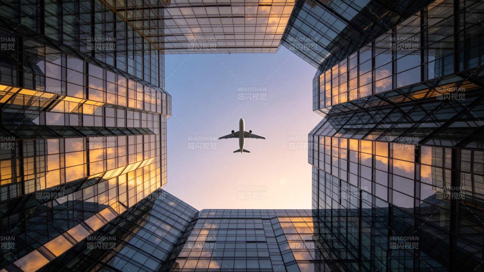 玻璃幕墙高楼间飞行的客机仰拍视角图片