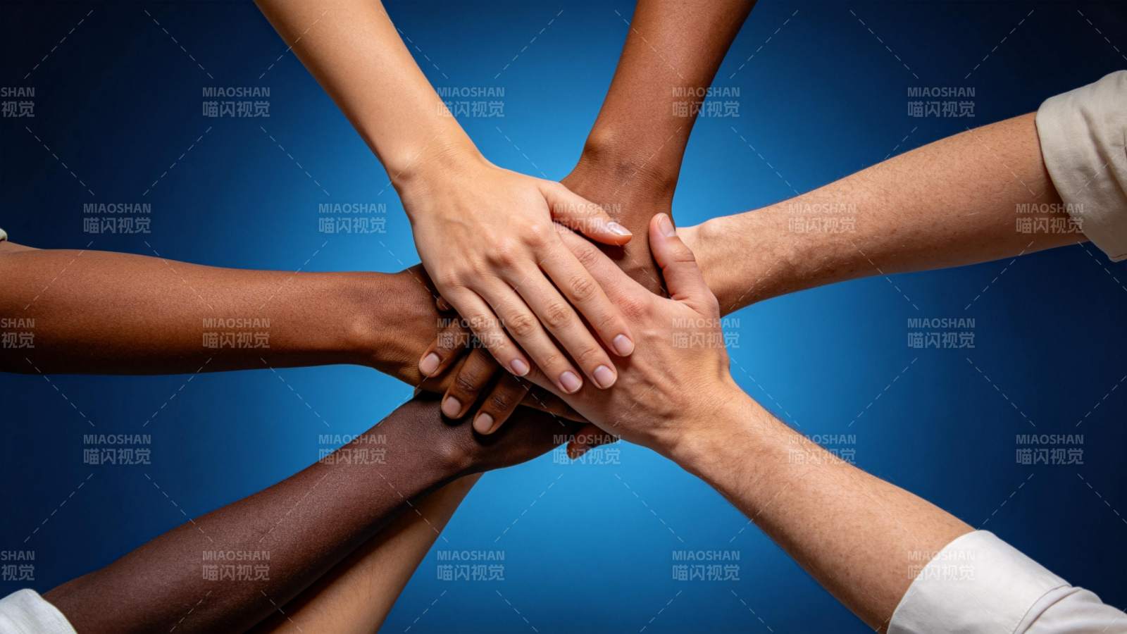 多只不同肤色手臂叠放形成团结手势图片