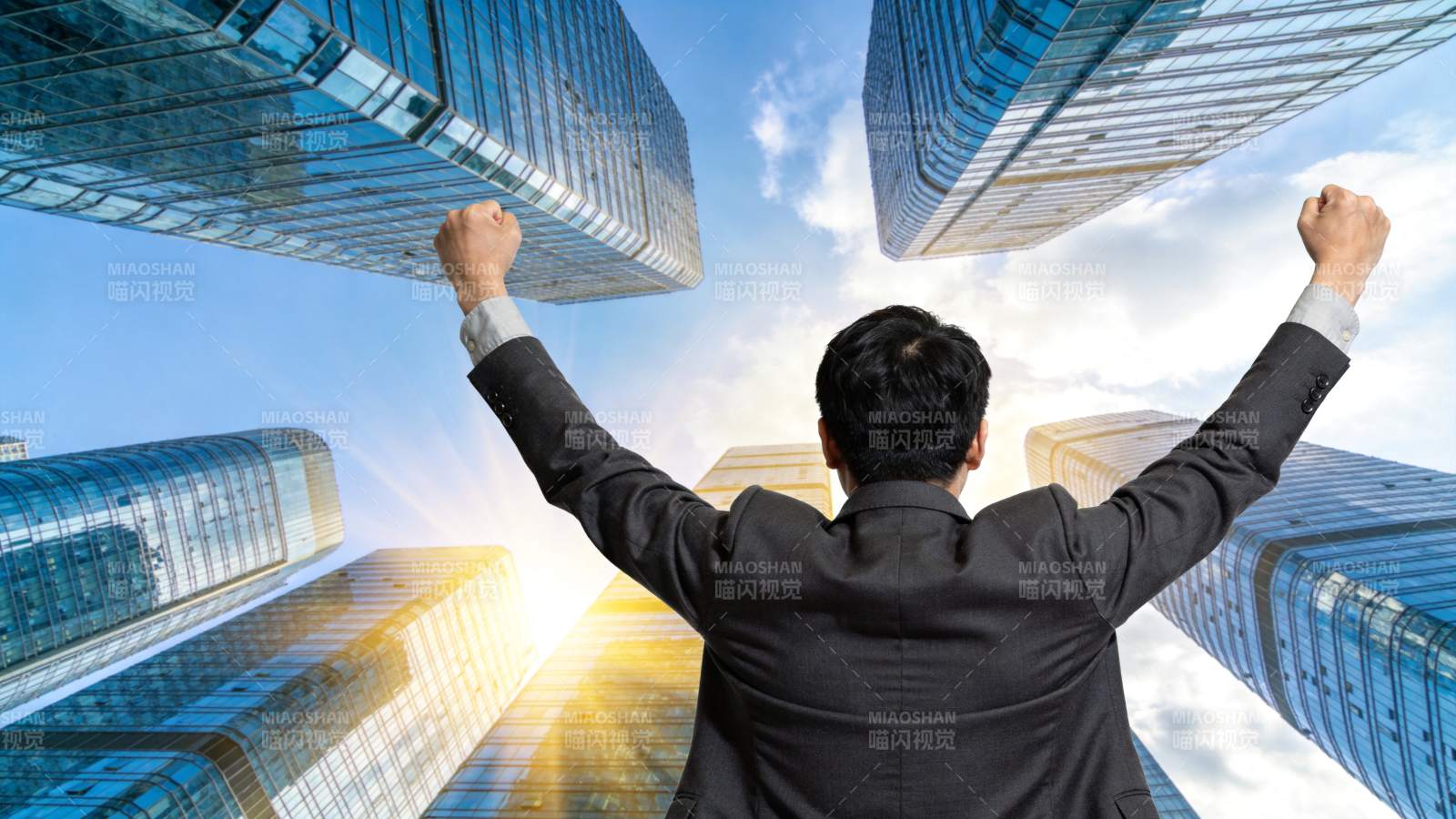 西装男子背影举拳仰望摩天大楼群图片
