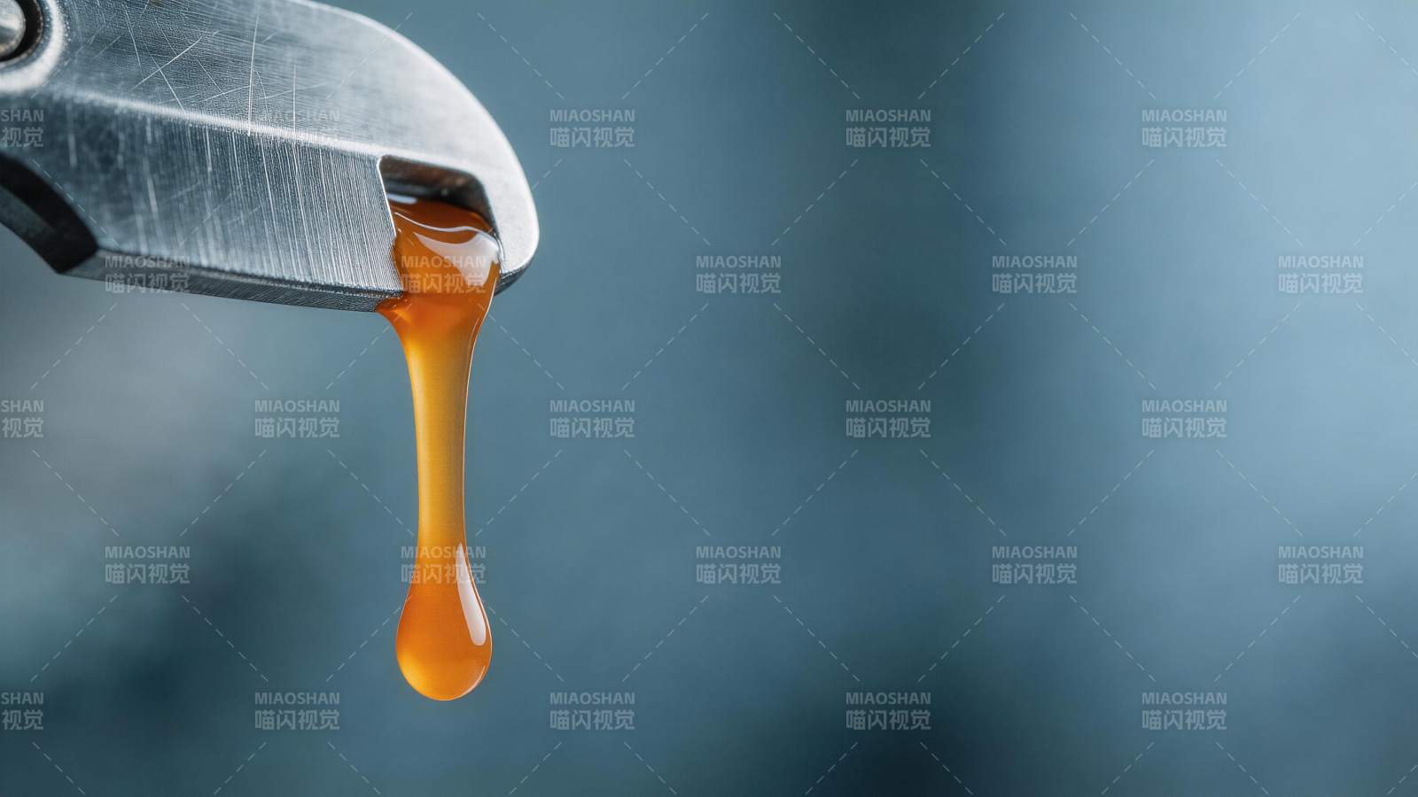金属钳口滴落琥珀色黏稠液体特写图片