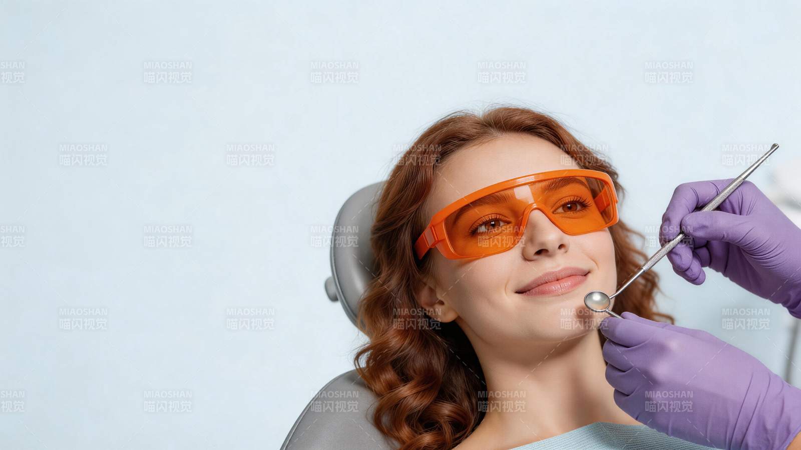 红发女子戴橙色护目镜接受牙科检查图片