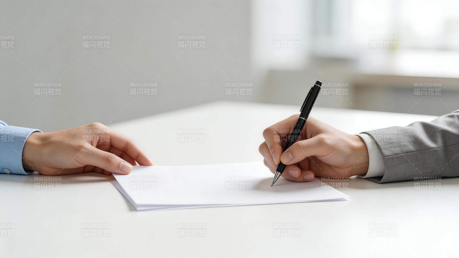 两人在白色桌面上签署文件的特写场景图片
