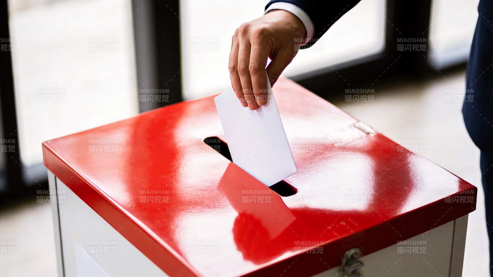 手将选票投入红色投票箱的特写画面图片