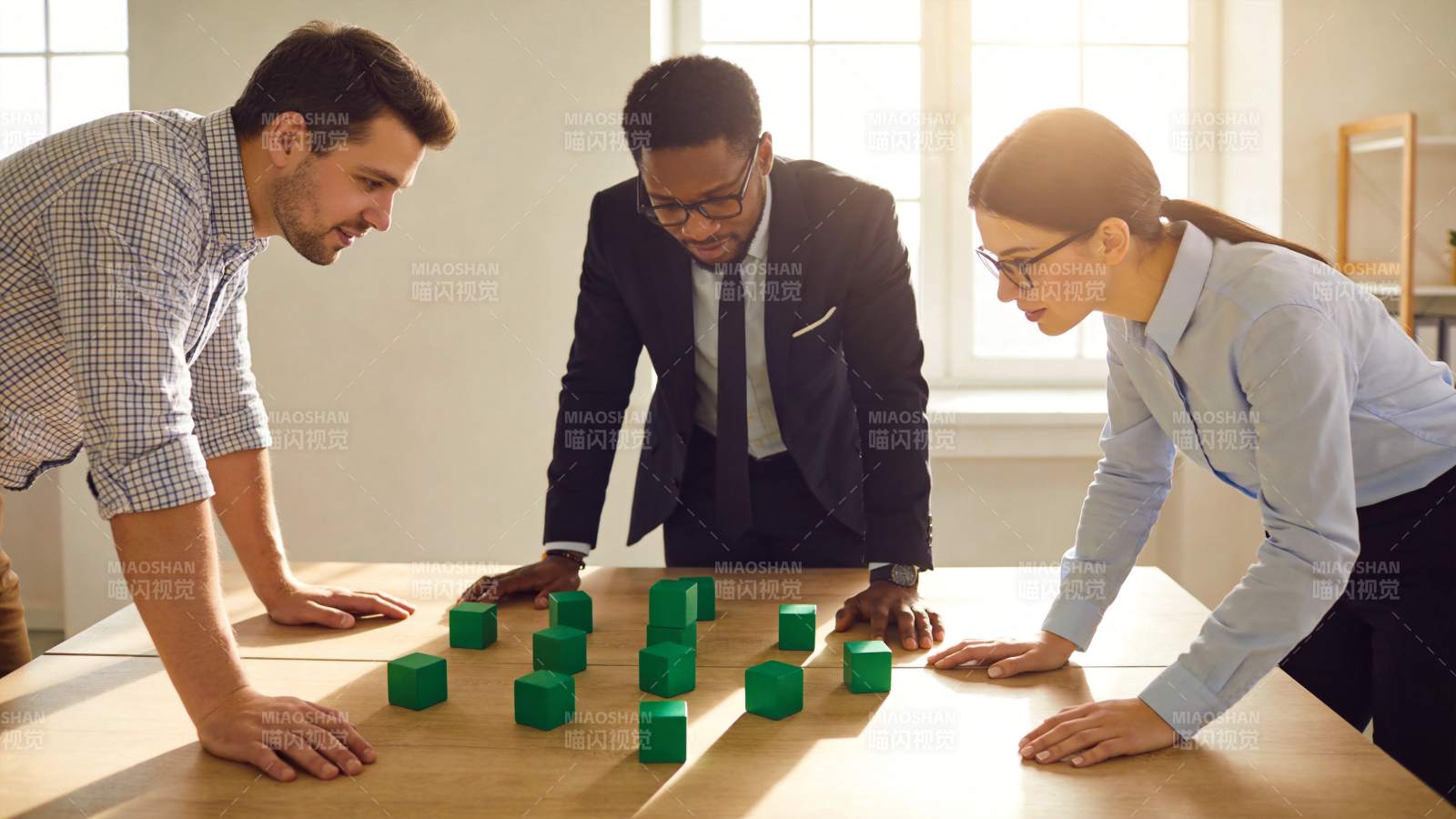 三位职场人士围桌分析绿色立方体积木模型图片