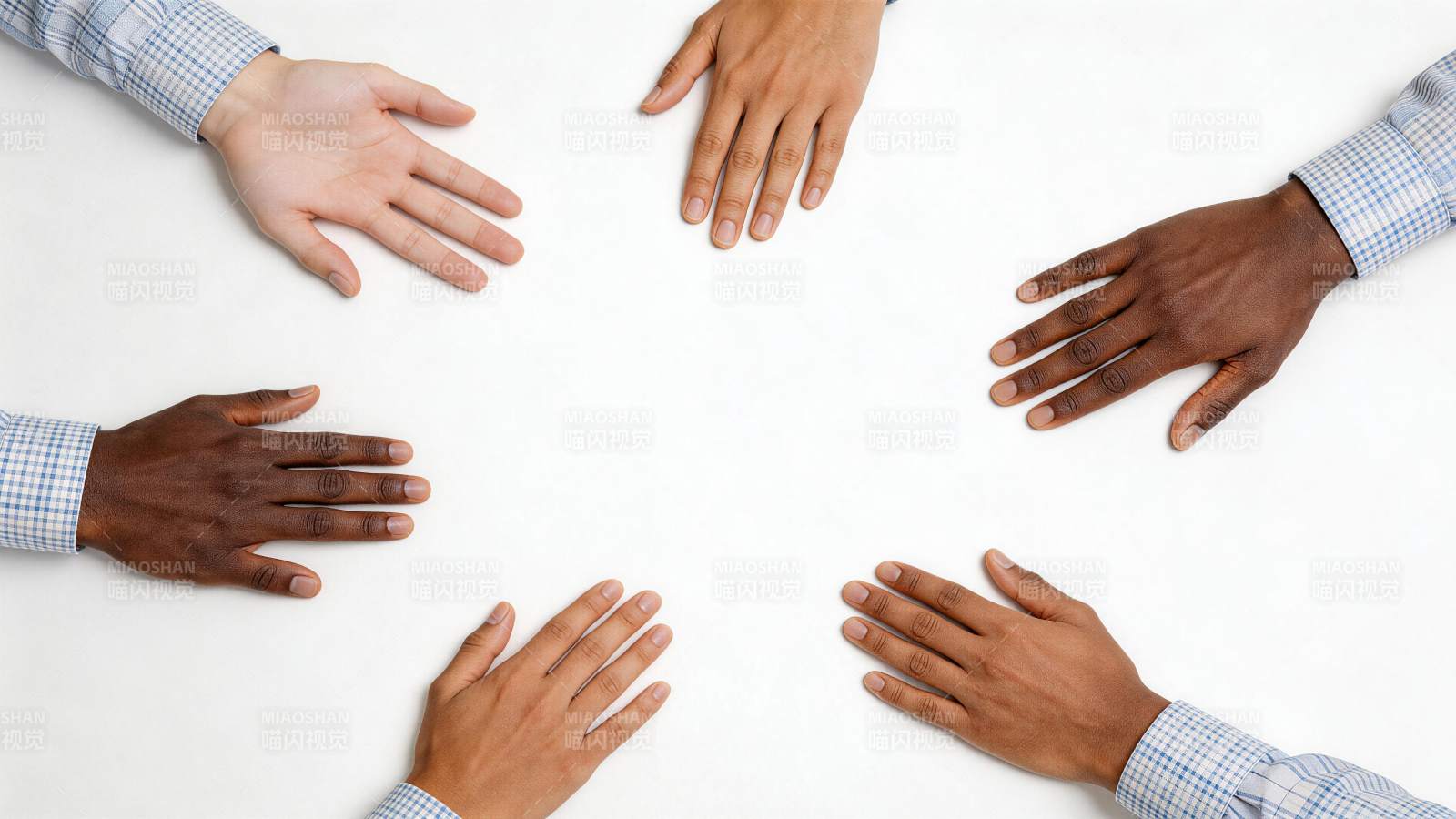 六只不同肤色手掌围成圆圈置于白桌面上图片