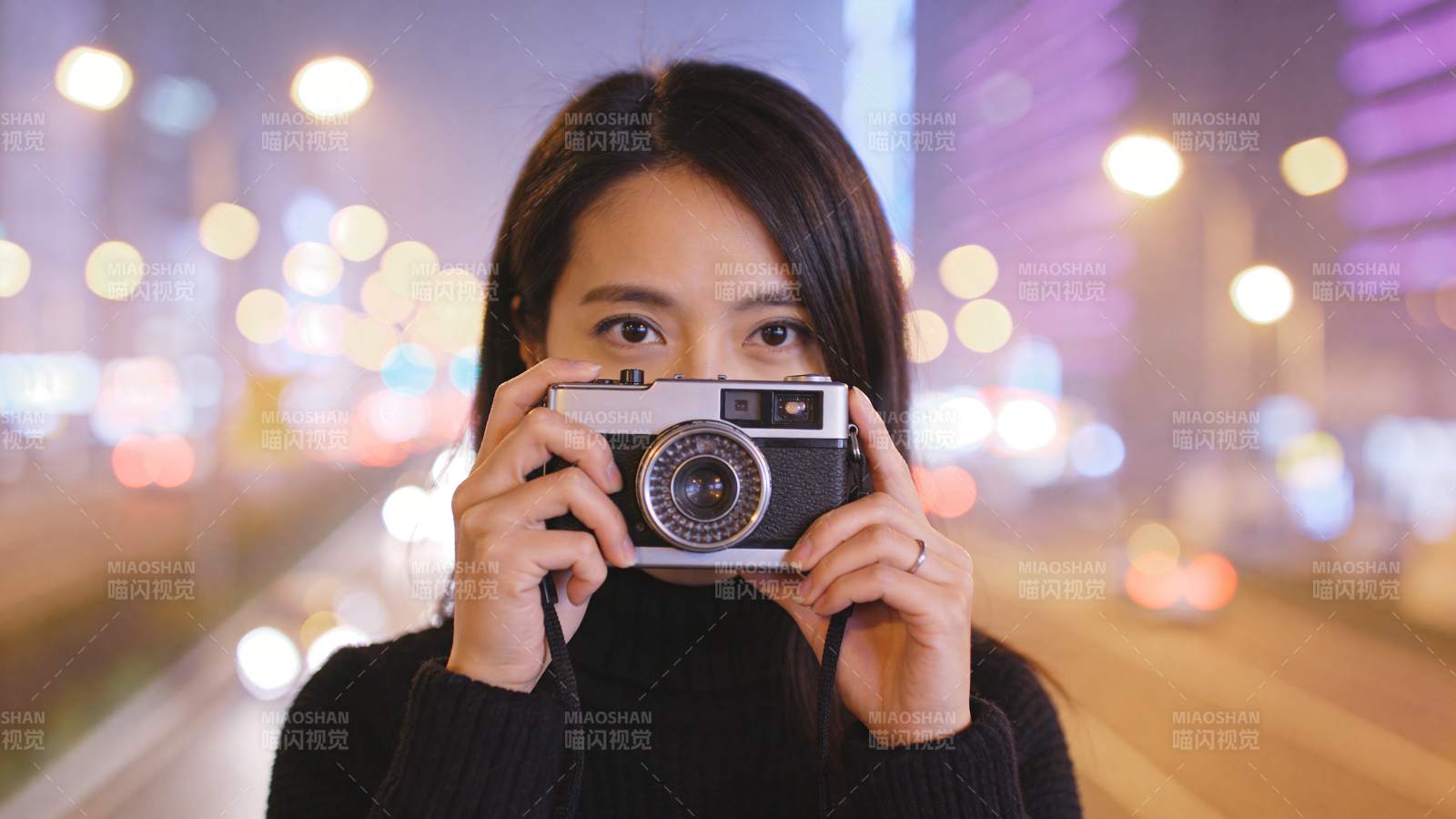 女子手持胶片相机夜拍城市街景图片