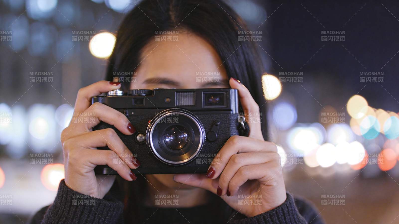女子手持老式相机夜间拍摄街景图片