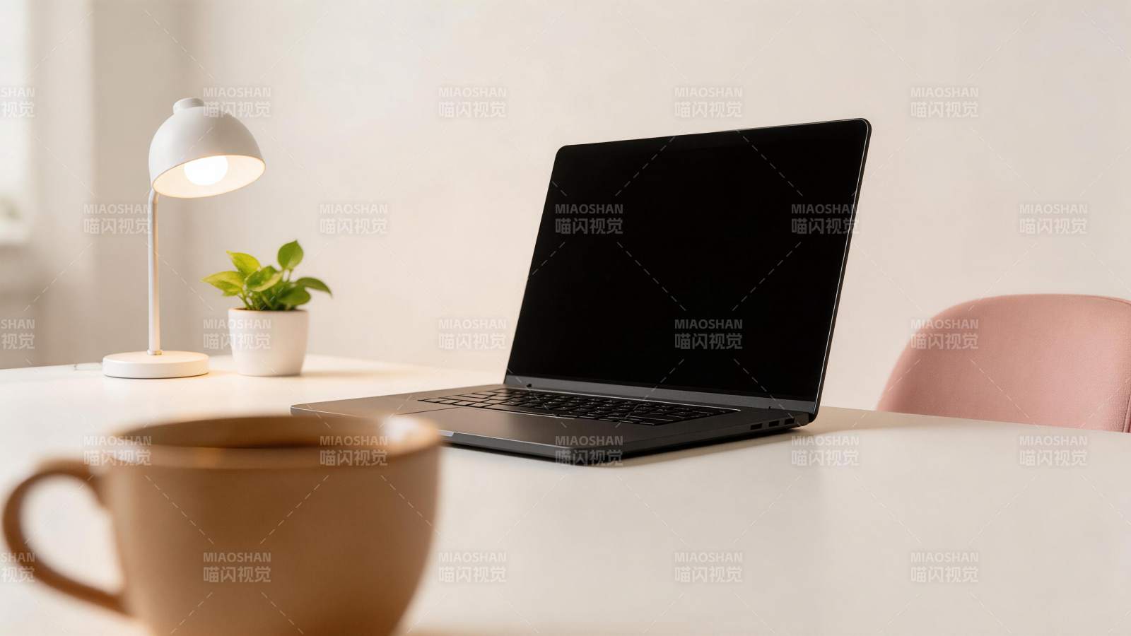 白色桌面上摆放笔记本电脑与台灯绿植咖啡杯图片