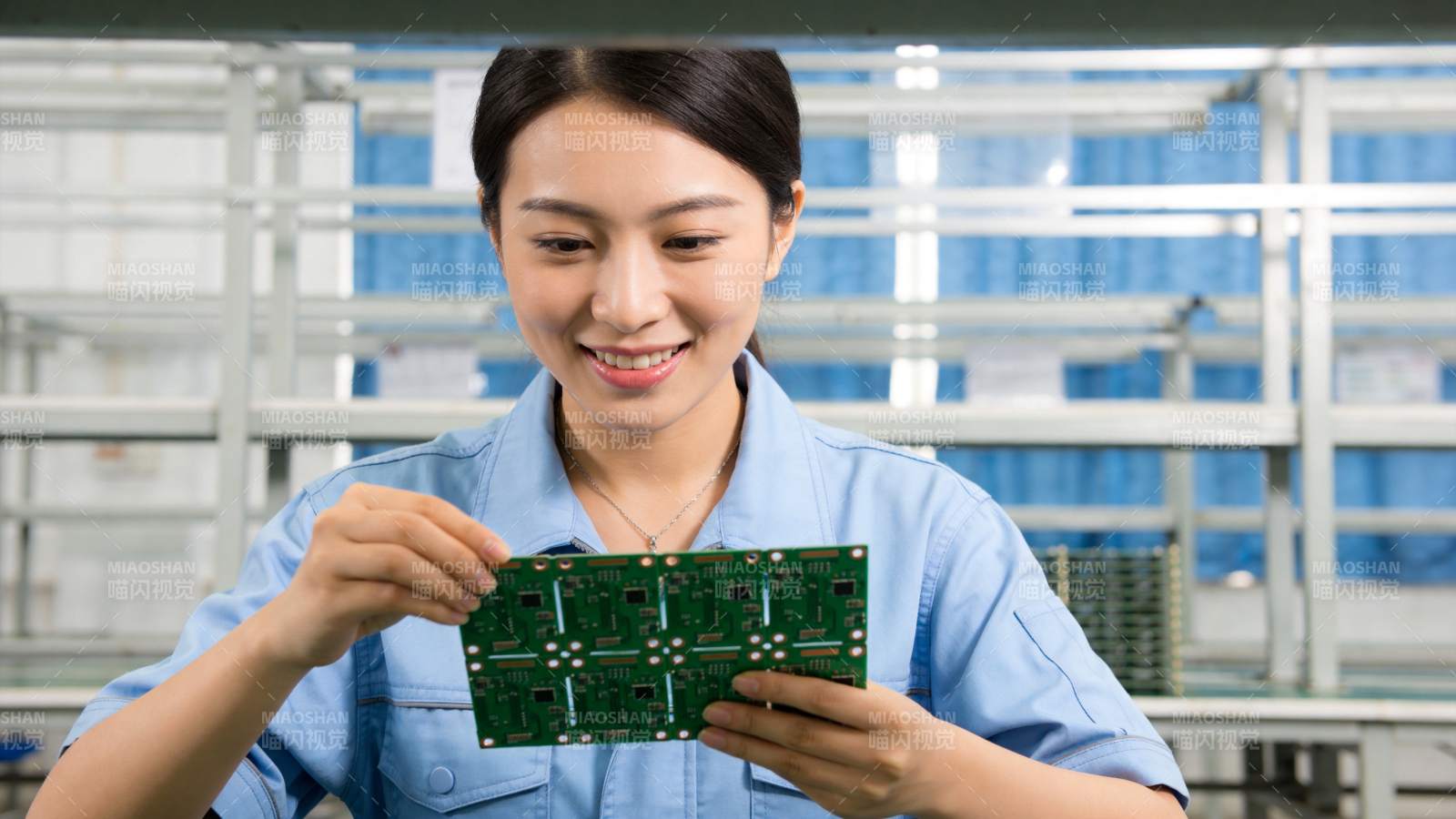 女工人手持绿色电路板进行质检作业图片