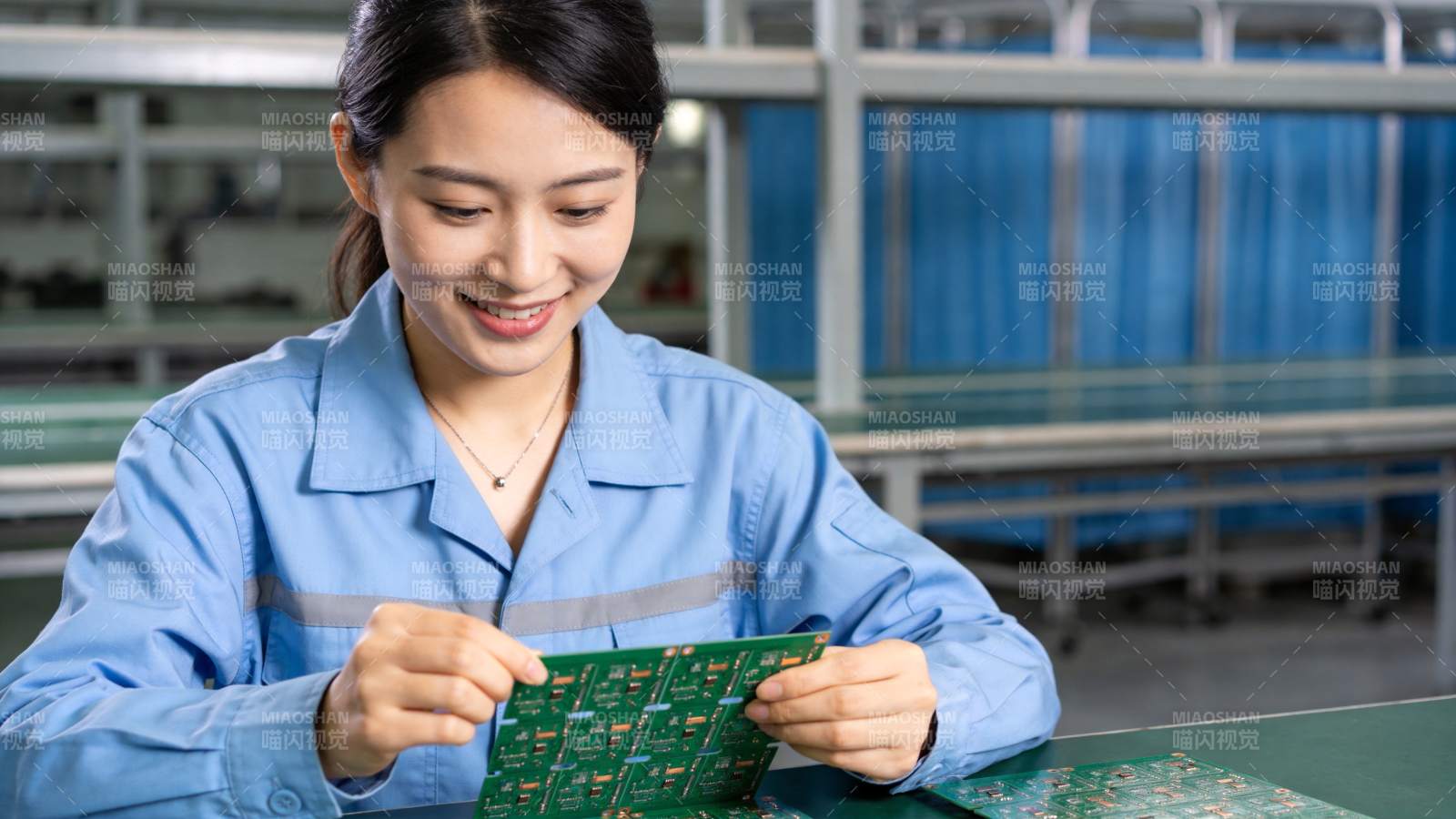 女工人在车间检查绿色电路板组件图片