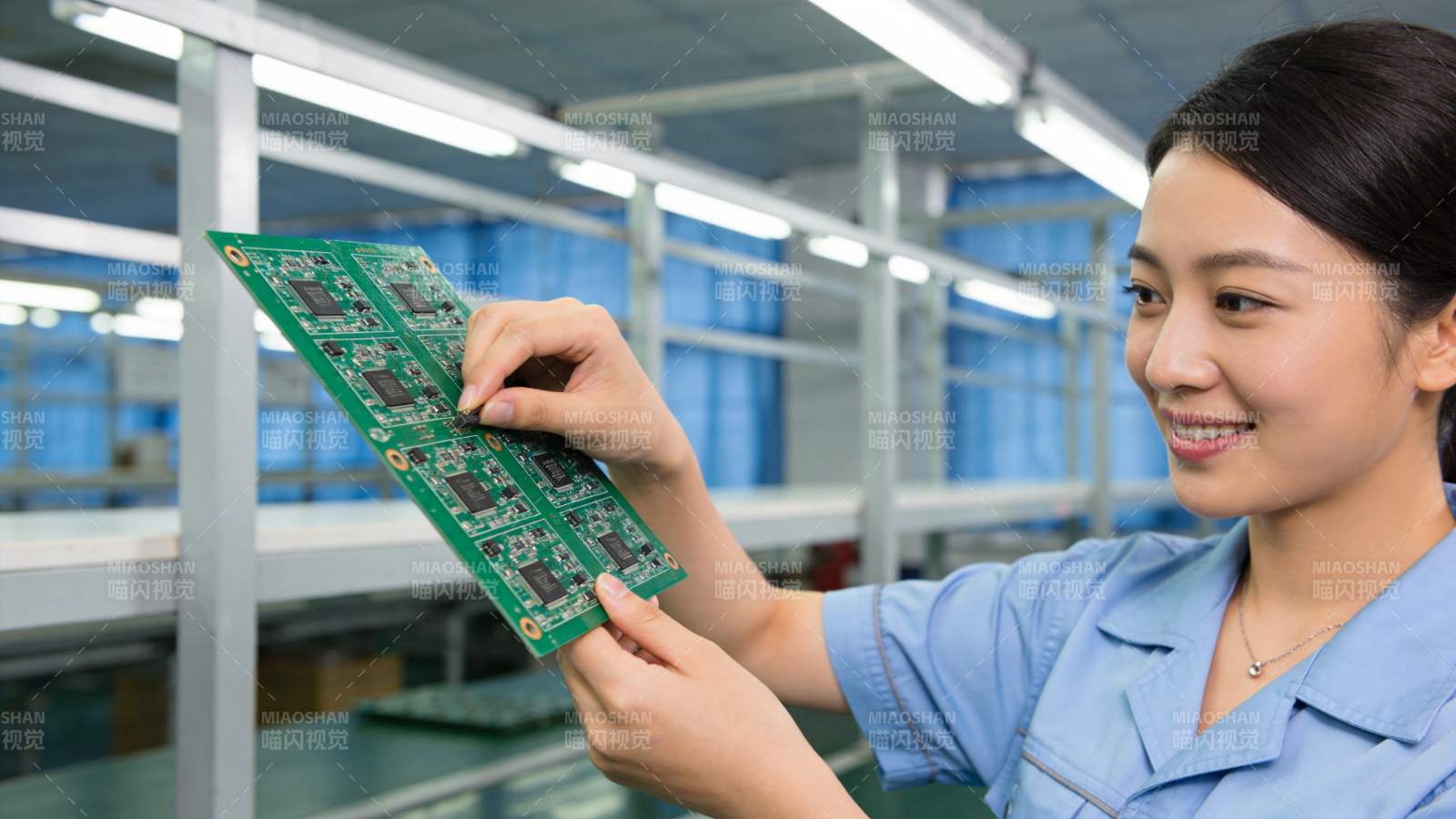 女工人手持绿色电路板进行质检作业图片