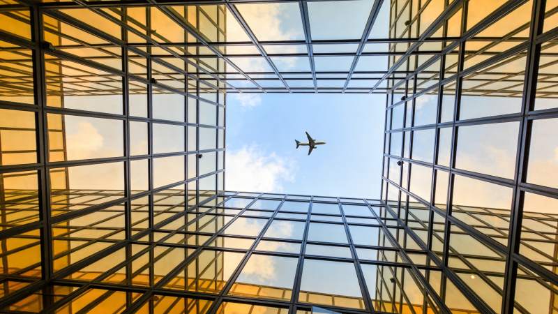 玻璃幕墙建筑仰视视角中飞行的客机图片