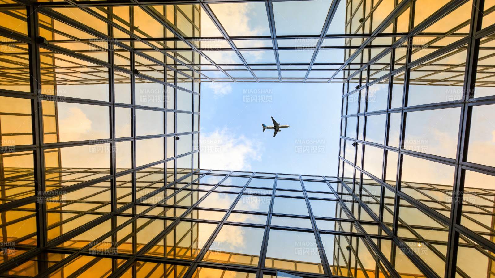 玻璃幕墙建筑仰视视角中飞行的客机图片