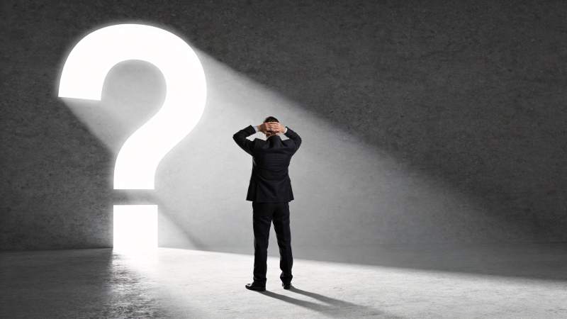西装男子面对发光问号陷入沉思图片