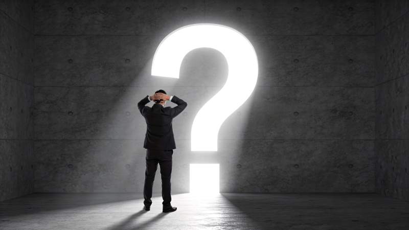 西装男子面对发光问号陷入沉思图片