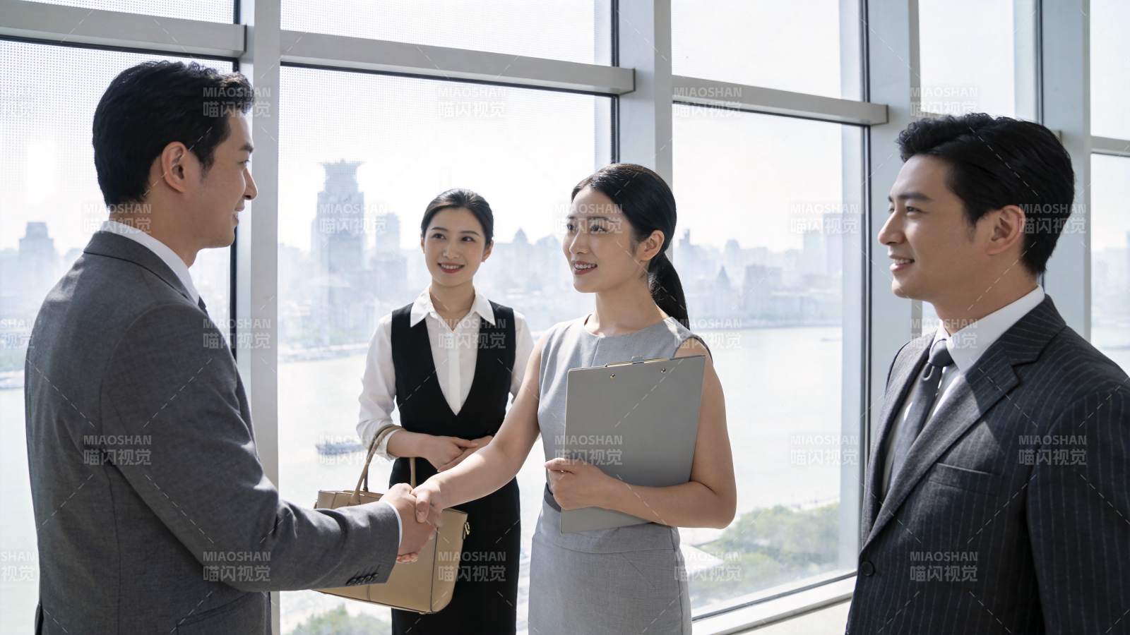 四位职场人士在办公室窗前握手交流图片