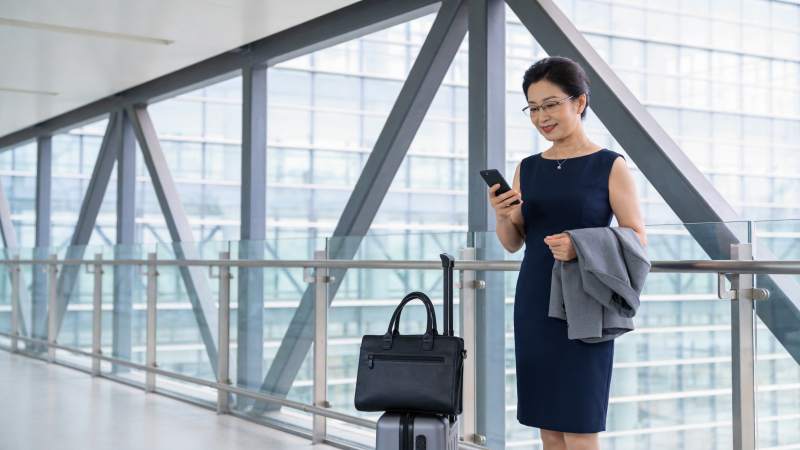 穿深蓝连衣裙女子在机场廊桥看手机图片