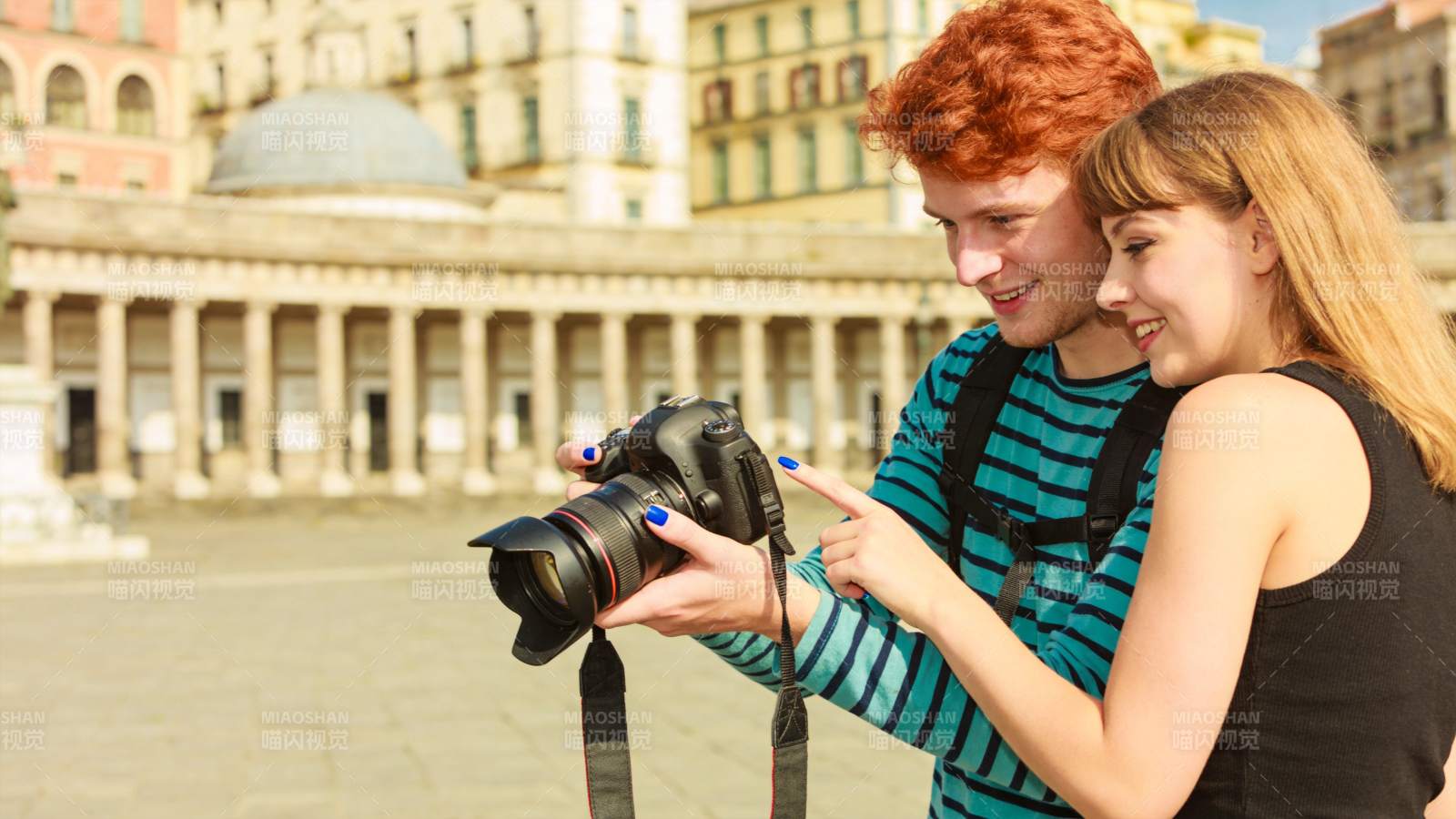红发男子与金发女子共同查看相机屏幕图片