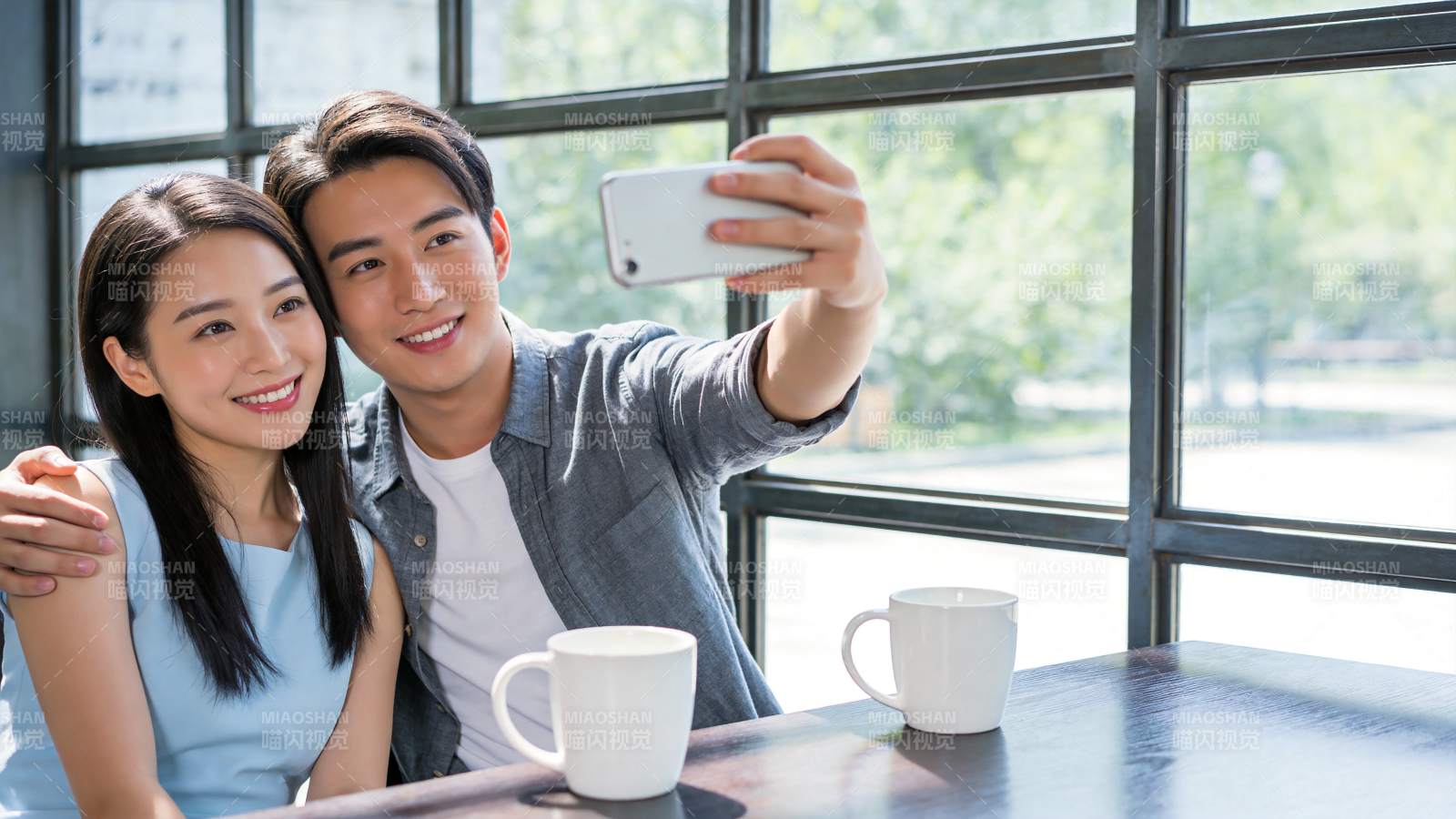 年轻男女在咖啡馆用手机自拍合影图片