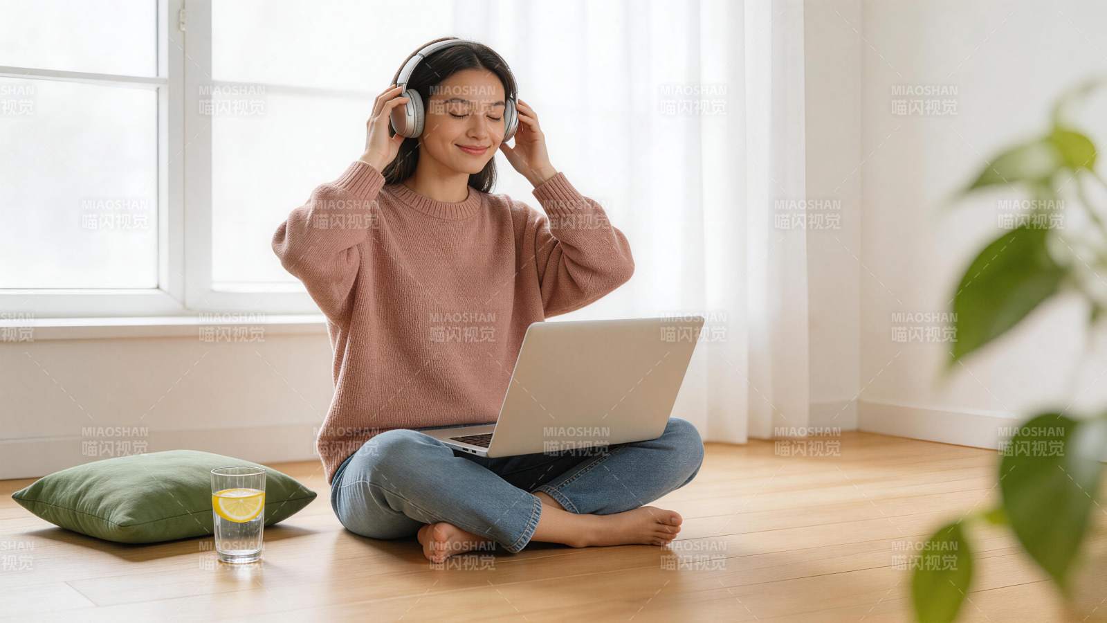 女子盘坐地板戴耳机使用笔记本电脑图片