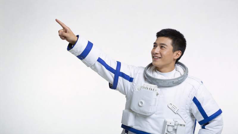 身穿白色宇航服男子指向右上方微笑图片