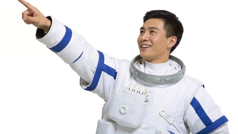 身穿白色宇航服男子指向右上方微笑图片