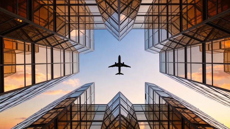 玻璃幕墙建筑间飞行的客机剪影图片