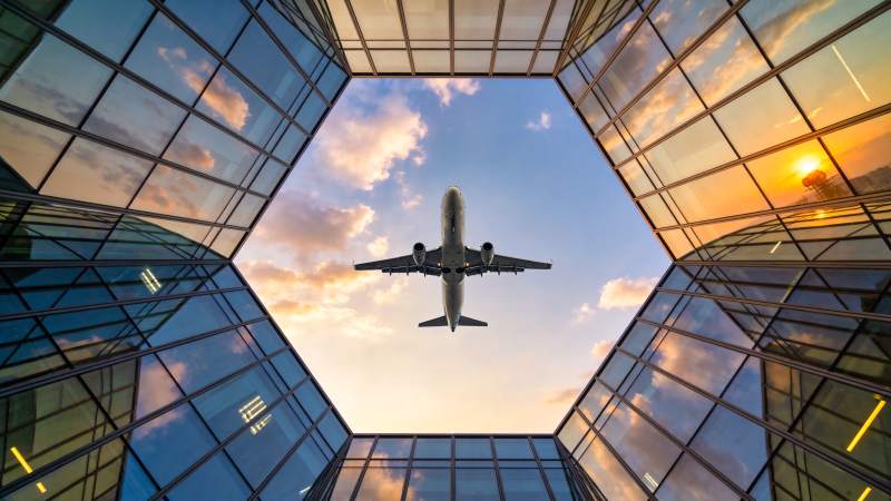 玻璃幕墙间飞机掠过夕阳天空图片