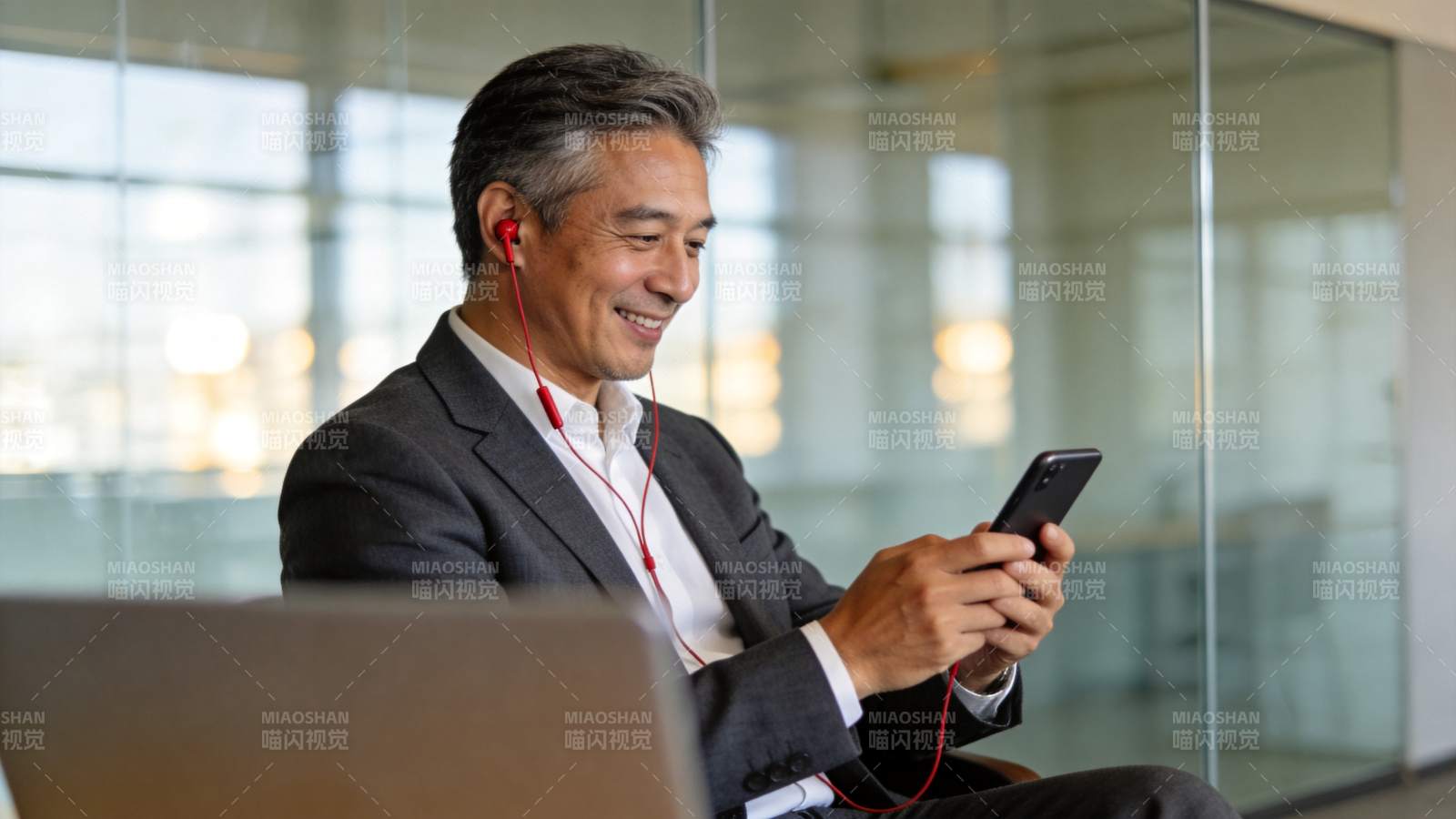 中年男子戴红耳机用手机办公微笑图片