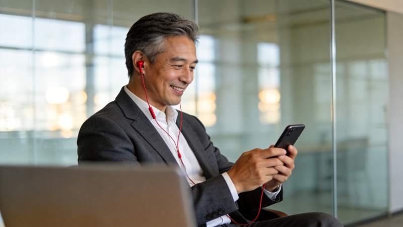 中年男子戴红耳机用手机办公微笑图片