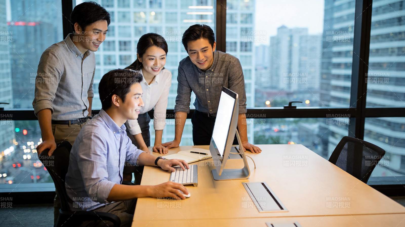 四位职场人员围看电脑屏幕讨论工作图片