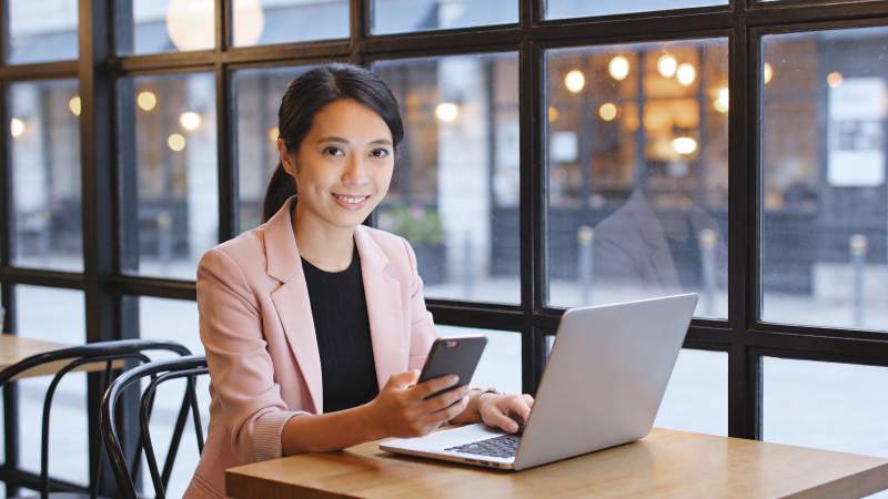 女性在咖啡馆使用笔记本电脑和手机工作图片