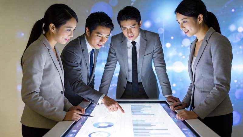 四位职场人士围绕互动触控屏分析数据图表图片