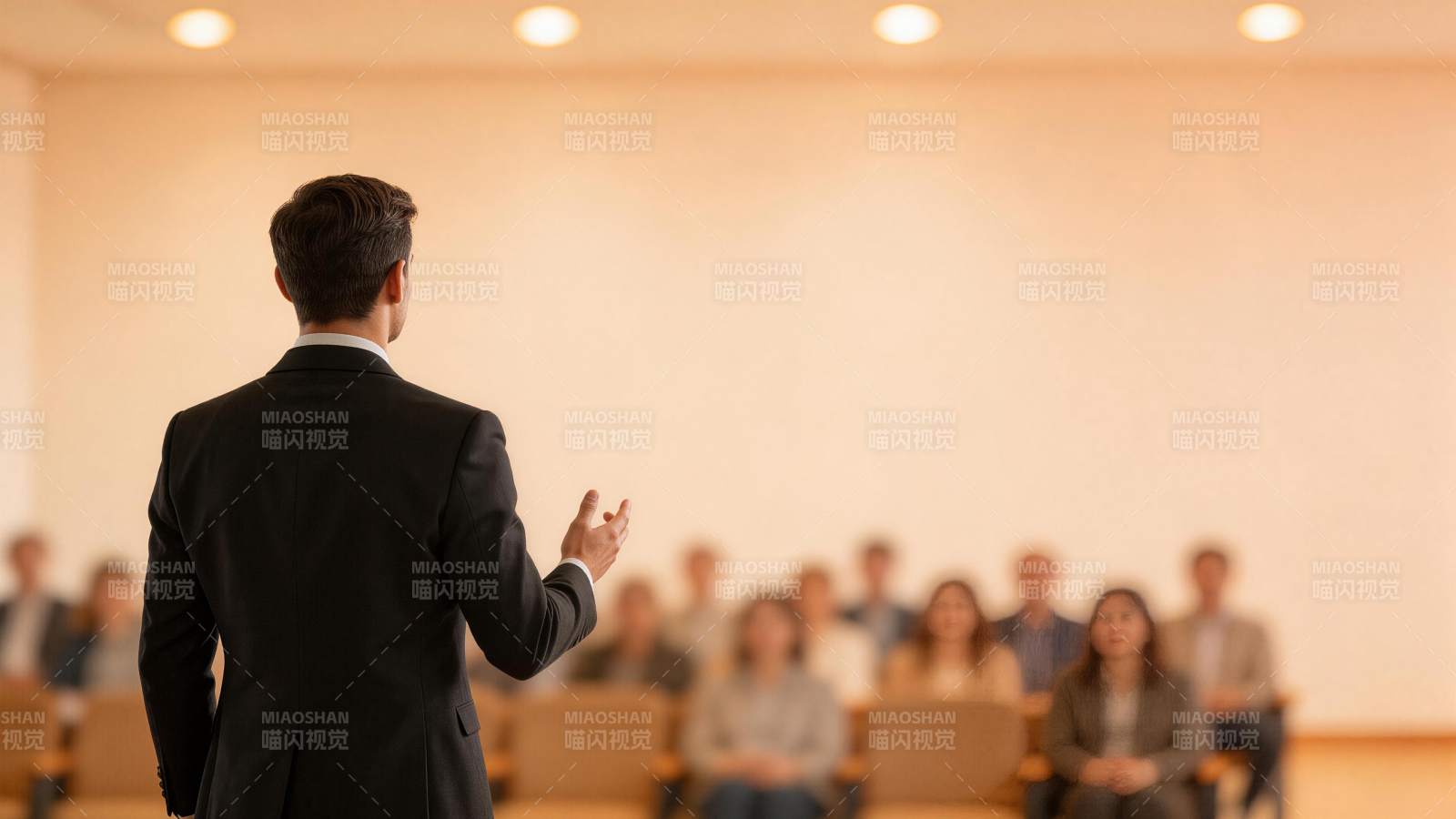 男士背对镜头在讲台前向听众演讲图片