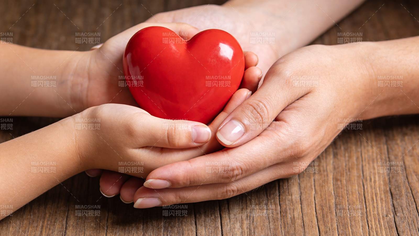 双手共同托举红色心形物体特写图片