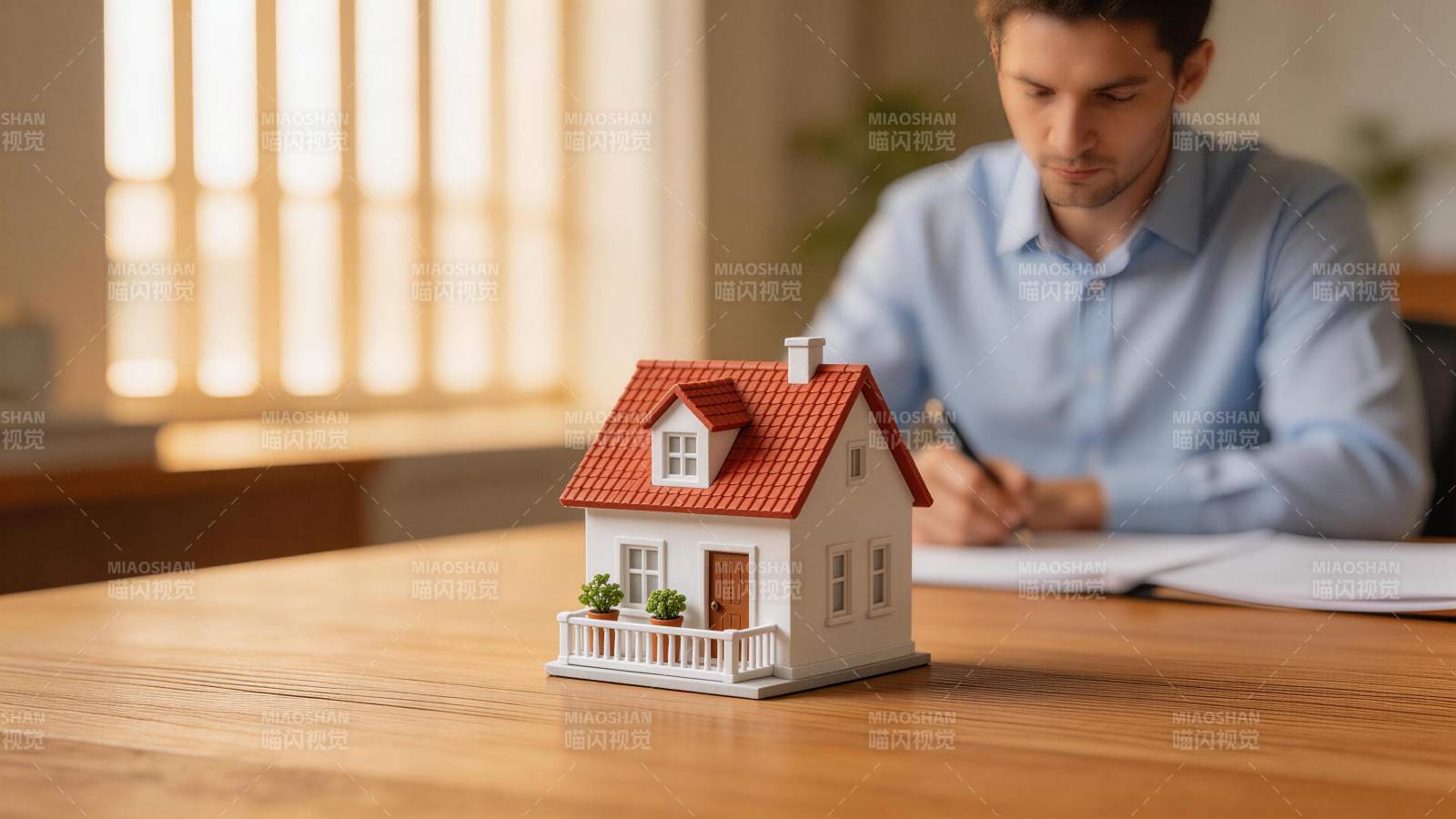 男子桌前签署文件旁置房屋模型图片