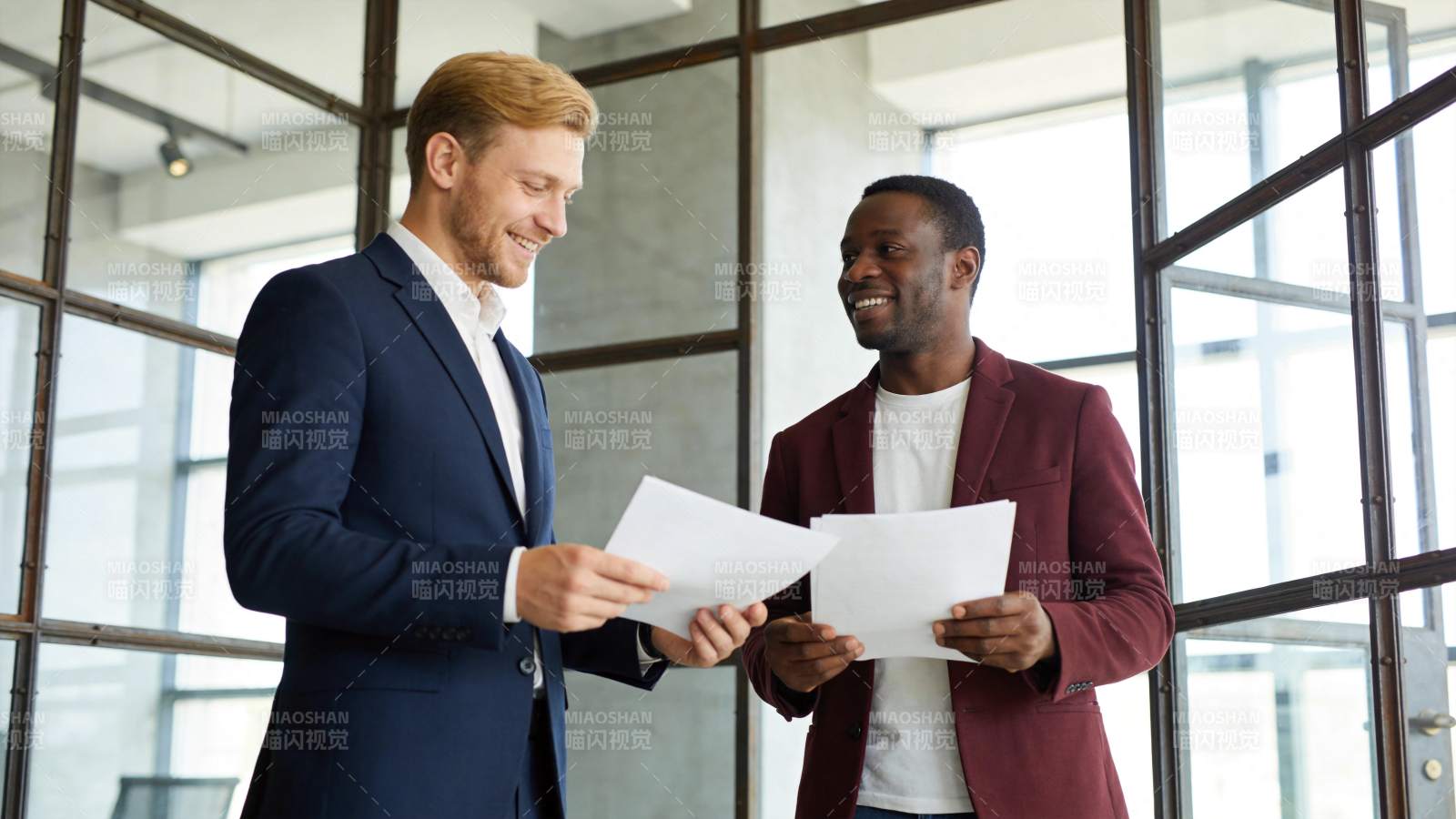 两位商务男士在办公室查看文件并交流图片