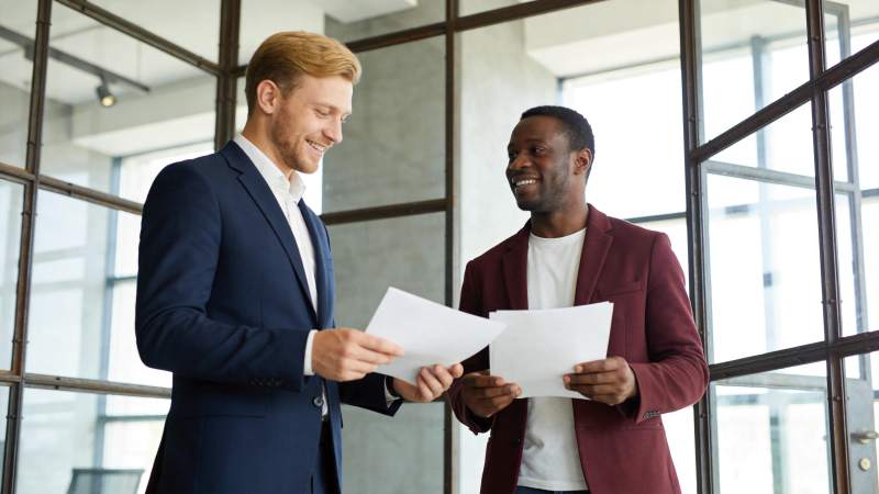 两位商务男士在办公室查看文件并交流图片