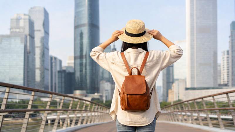 女子戴草帽背背包站在城市天桥远望高楼图片