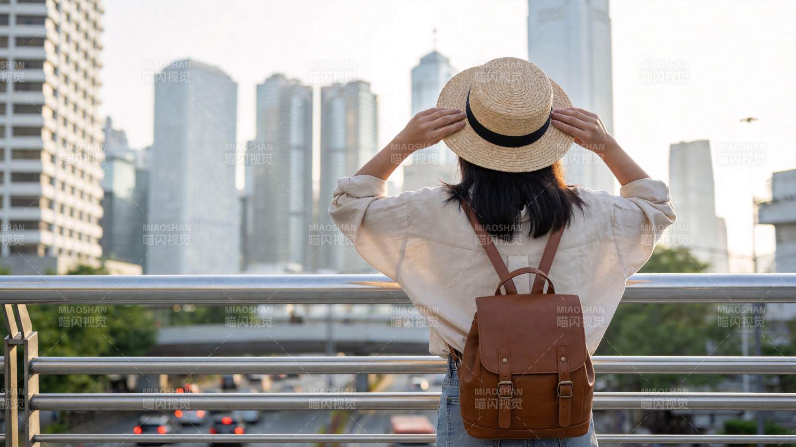 女子戴草帽背背包眺望城市高楼景观图片