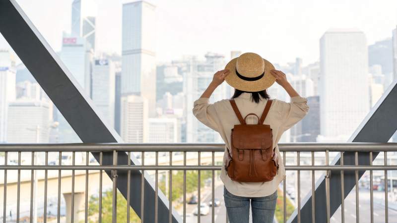 女子戴草帽背背包眺望城市高楼景观图片