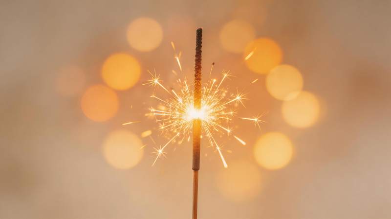 点燃的烟花棒在暖光虚化背景中绽放火花图片