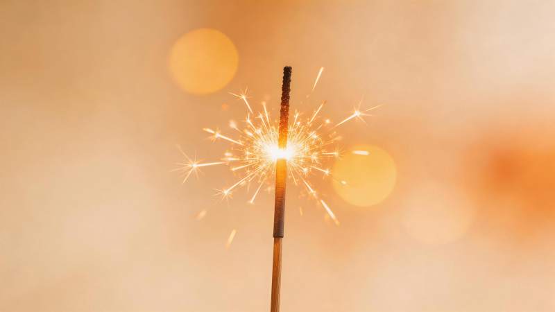 点燃的烟花棒迸发金色火花特写图片