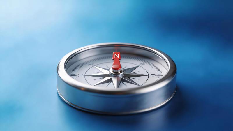 金属指南针置于蓝色背景上指示北方图片