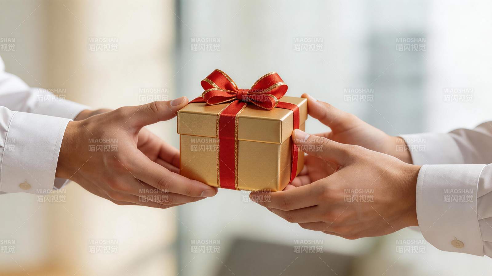 双手交接金色礼盒红色蝴蝶结装饰图片