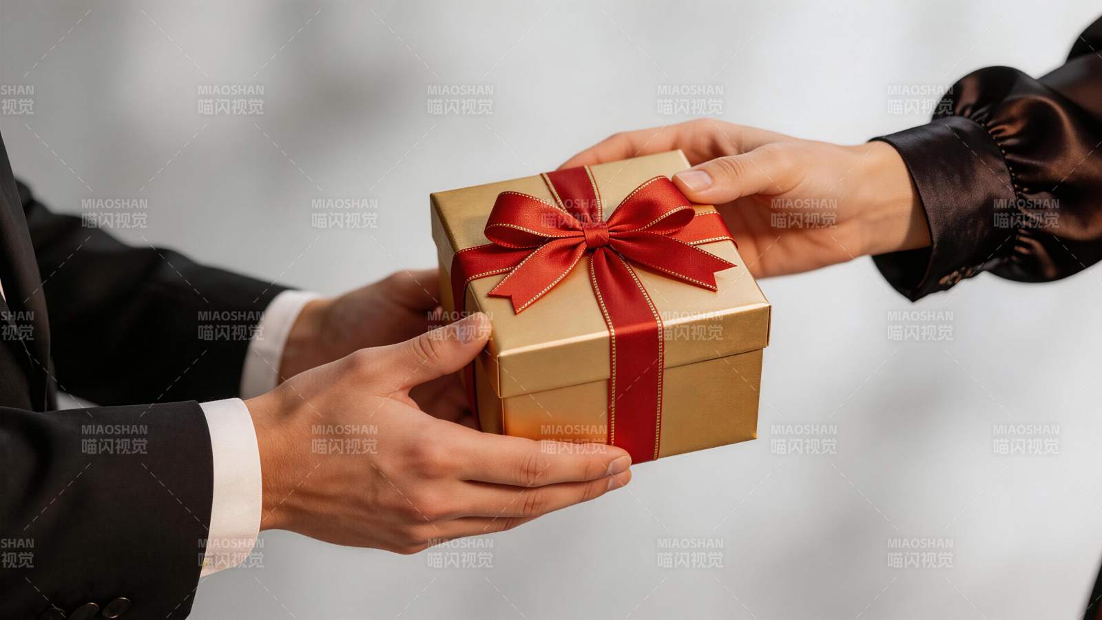 两人交接金色礼盒红色蝴蝶结礼物图片