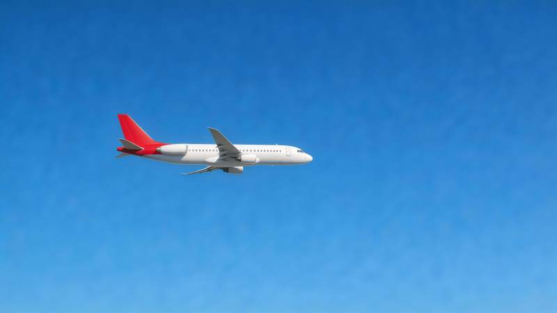 白色客机红尾翼蓝天飞行中图片